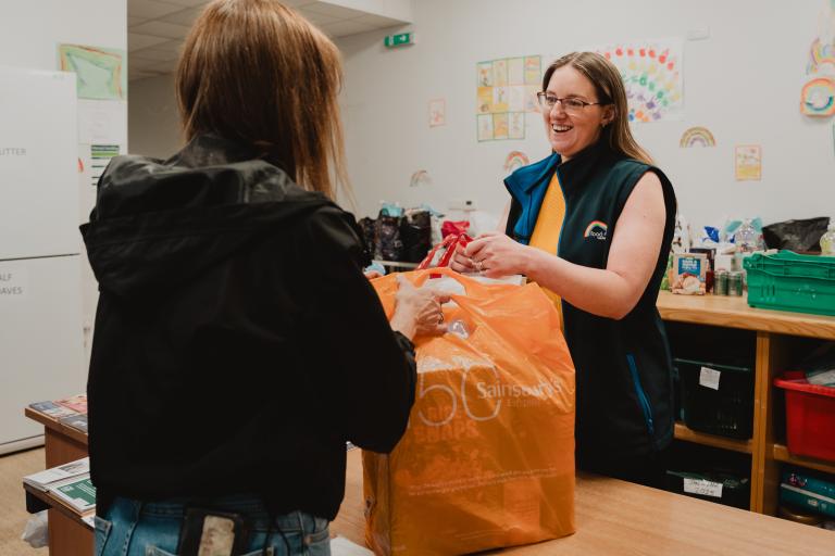 Person handing over shopping bag with food
