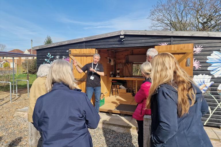 Group of attendees at the Spring into Community Food Growing event listening to a talk from Adam outside the Seed Shed at Gosling Sike