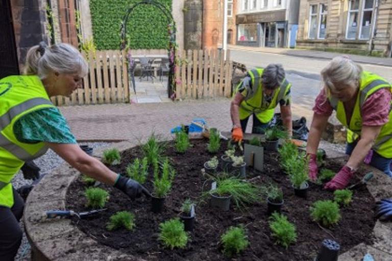 Members of Cockermouth Rotary tending to a planter filled with herbs