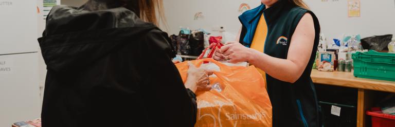 Person handing over shopping bag with food 
